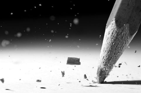 Pencil writing on hard surface with fragments of the pencil in the air.