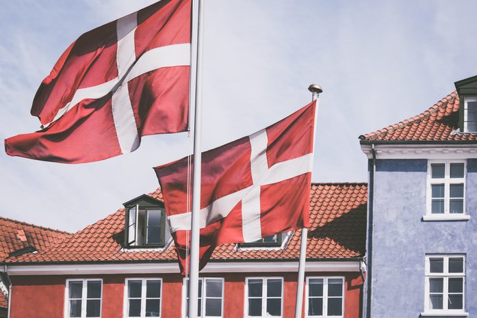 Two Danish flags in front of a red house.
