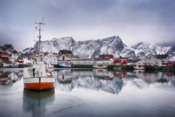 Fishing boat at sea with snowy mountains. Photo.