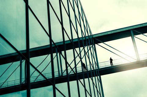 Building with man on bridge. Photo.